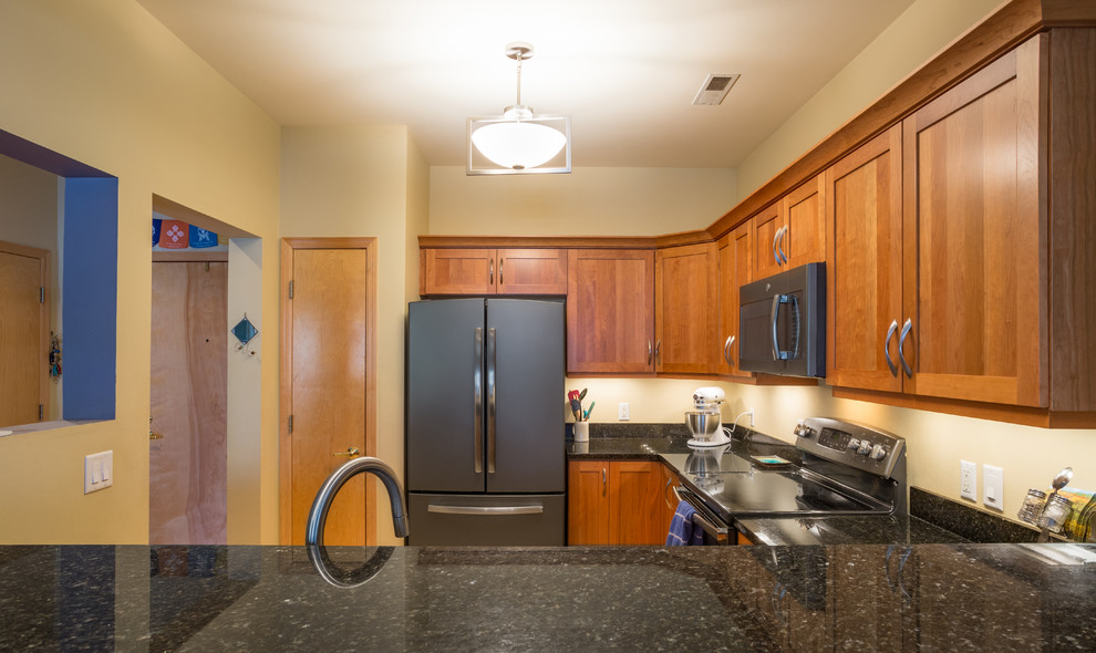 Inspiration for a mid-sized transitional u-shaped light wood floor open concept kitchen remodel with an undermount sink, shaker cabinets, medium tone wood cabinets, granite countertops, black appliances, no island and black countertops
