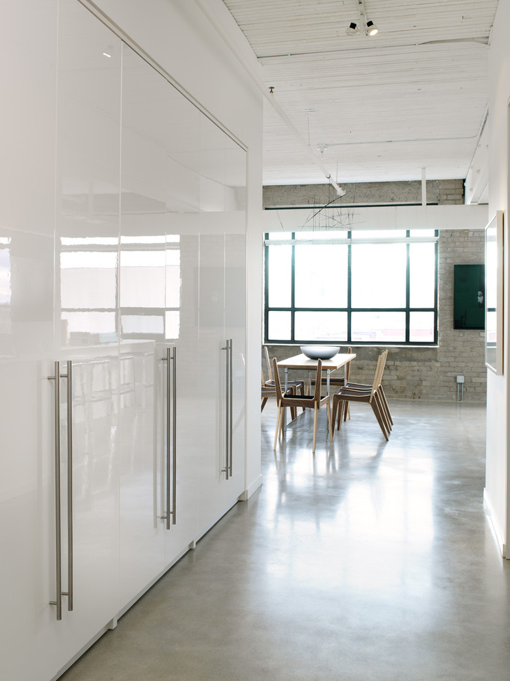 Photo of a large industrial entry hall in Toronto with white walls, concrete floors, a single front door, a gray front door and grey floor.