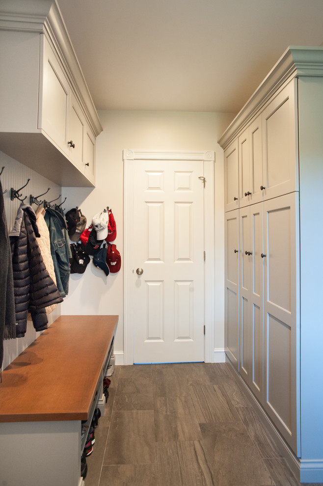 Mudroom - mid-sized transitional ceramic tile and brown floor mudroom idea in Boston with beige walls and a white front door