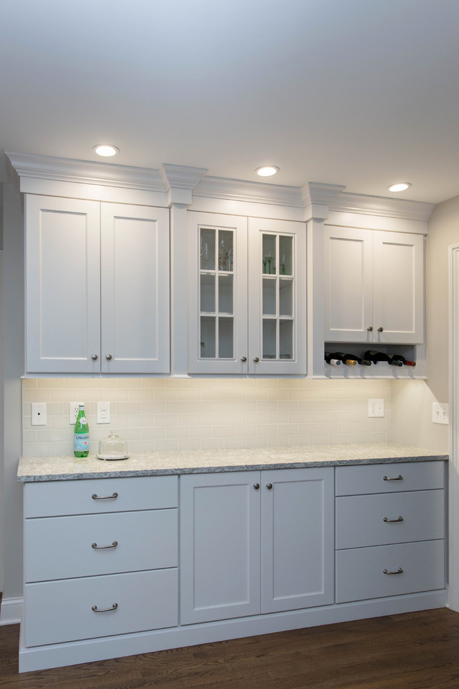 Inspiration for a mid-sized transitional u-shaped dark wood floor enclosed kitchen remodel in Boston with an undermount sink, recessed-panel cabinets, white cabinets, quartz countertops, gray backsplash, subway tile backsplash, stainless steel appliances and an island