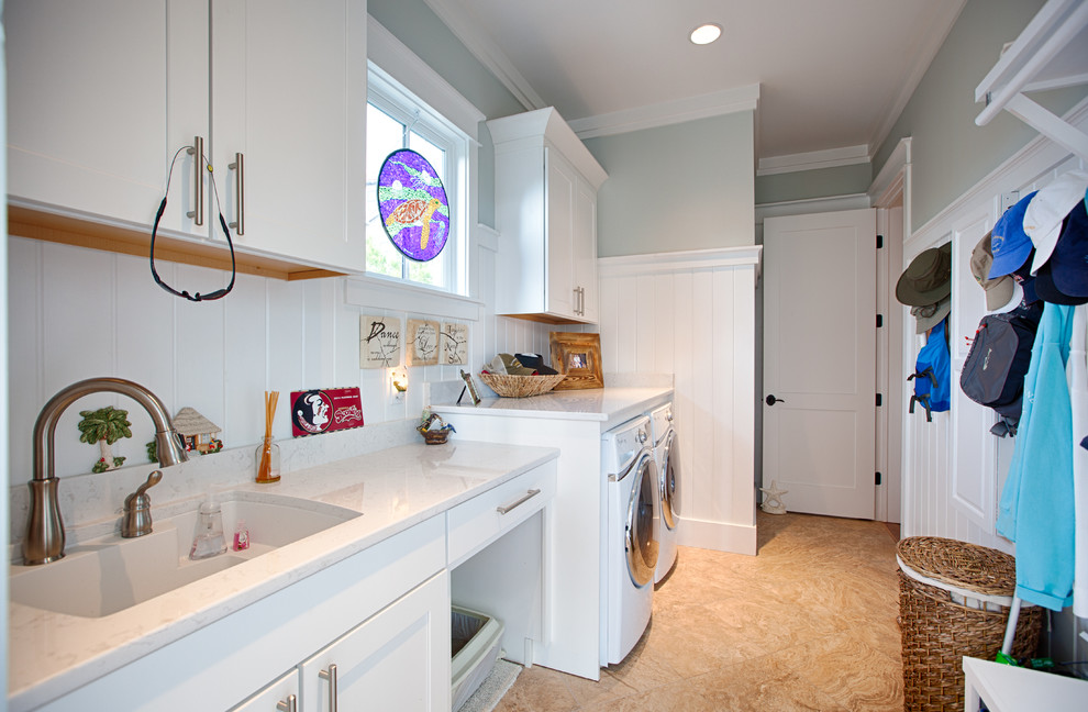 This is an example of a mid-sized beach style single-wall dedicated laundry room in Miami with an undermount sink, shaker cabinets, white cabinets, quartz benchtops, grey walls, porcelain floors, a side-by-side washer and dryer, beige floor and white benchtop.