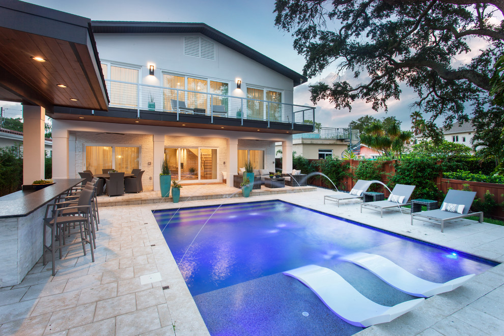 This is an example of a large contemporary backyard rectangular lap pool in Tampa with natural stone pavers.