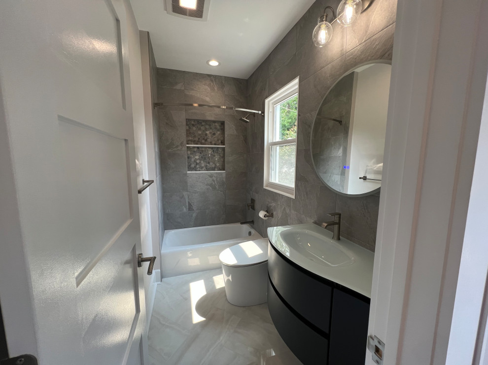 Стильный дизайн: маленькая ванная комната в стиле модернизм с плоскими фасадами, синими фасадами, ванной в нише, душем над ванной, унитазом-моноблоком, серой плиткой, керамогранитной плиткой, серыми стенами, полом из керамогранита, монолитной раковиной, стеклянной столешницей, бежевым полом, зеленой столешницей, нишей, тумбой под одну раковину и подвесной тумбой для на участке и в саду - последний тренд