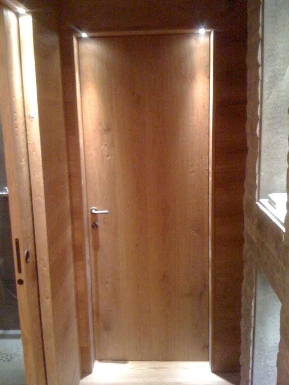 Example of a mid-sized mountain style medium tone wood floor mudroom design in Milan with gray walls and a medium wood front door
