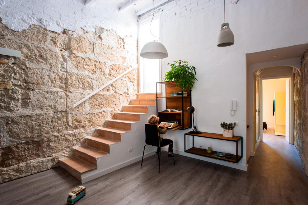 Modelo de sala de estar con biblioteca tipo loft industrial de tamaño medio con paredes blancas, suelo de madera oscura y vigas vistas