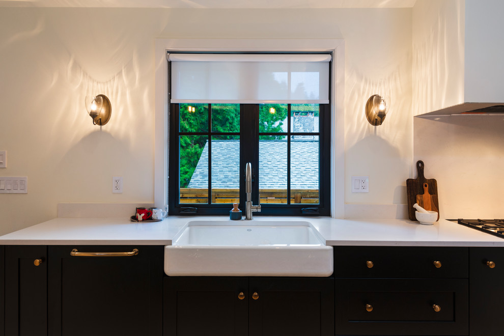 Mid-sized mountain style l-shaped light wood floor and beige floor open concept kitchen photo in Vancouver with a farmhouse sink, shaker cabinets, black cabinets, quartz countertops, paneled appliances, an island and white countertops