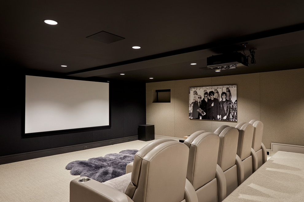 This is an example of a mid-sized transitional enclosed home theatre in New York with black walls, carpet, a projector screen and beige floor.