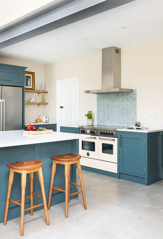 This is an example of a mid-sized traditional l-shaped eat-in kitchen in London with shaker cabinets, blue cabinets, quartzite benchtops, with island and white benchtop.