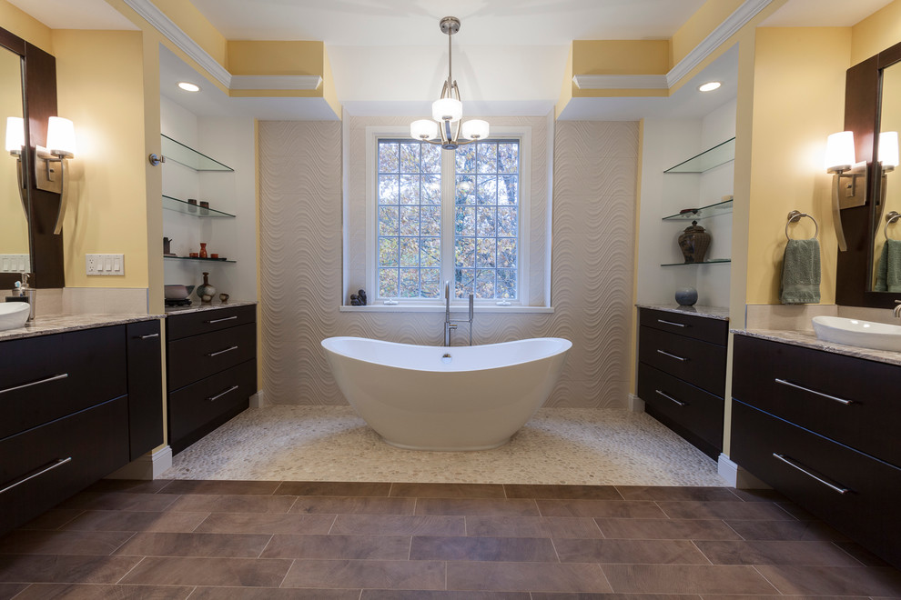 Design ideas for a large contemporary master bathroom in New York with flat-panel cabinets, brown cabinets, a freestanding tub, a corner shower, a two-piece toilet, white tile, porcelain tile, yellow walls, pebble tile floors, a vessel sink, quartzite benchtops, beige floor and a hinged shower door.