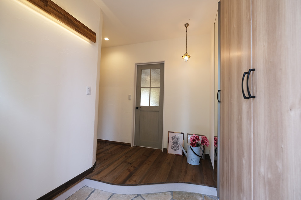 This is an example of a country entryway in Fukuoka with white walls, dark hardwood floors, a single front door and a medium wood front door.