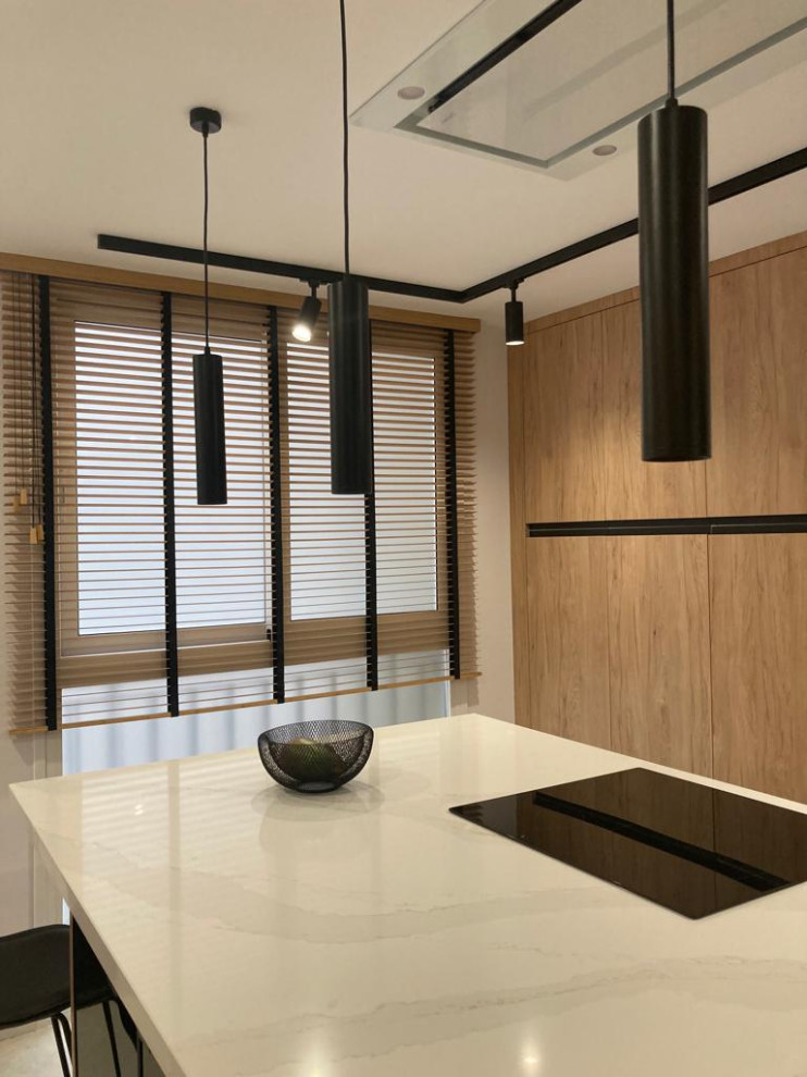 This is an example of a mid-sized modern l-shaped open plan kitchen in Seville with an undermount sink, glass-front cabinets, medium wood cabinets, quartz benchtops, porcelain splashback, black appliances, porcelain floors, with island, grey floor and white benchtop.
