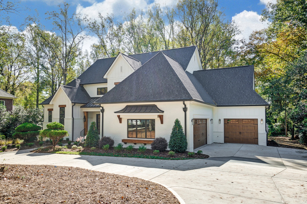 Großes, Zweistöckiges Landhaus Einfamilienhaus mit gestrichenen Ziegeln, weißer Fassadenfarbe, Satteldach, Schindeldach, schwarzem Dach und Wandpaneelen in Charlotte