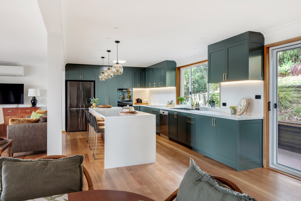 Eat-in kitchen - large transitional l-shaped medium tone wood floor and multicolored floor eat-in kitchen idea in Sydney with a drop-in sink, shaker cabinets, green cabinets, quartz countertops, white backsplash, quartz backsplash, black appliances, an island and white countertops