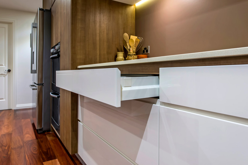Large contemporary galley eat-in kitchen in Perth with an undermount sink, flat-panel cabinets, white cabinets, quartz benchtops, brown splashback, porcelain splashback, stainless steel appliances, dark hardwood floors and with island.