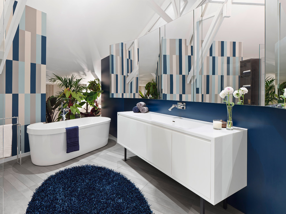 This is an example of a large contemporary bathroom in Stuttgart with flat-panel cabinets, white cabinets, a freestanding tub, blue walls and an integrated sink.