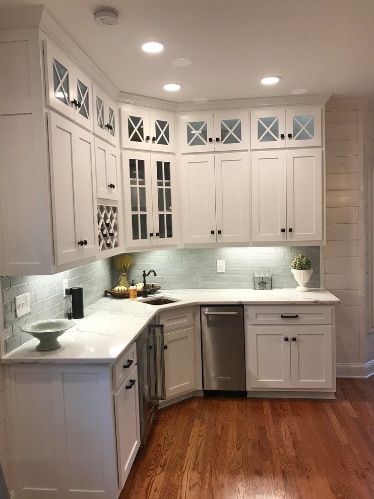 Inspiration for a mid-sized transitional u-shaped medium tone wood floor and brown floor eat-in kitchen remodel in Atlanta with a farmhouse sink, shaker cabinets, white cabinets, subway tile backsplash, stainless steel appliances, an island and granite countertops