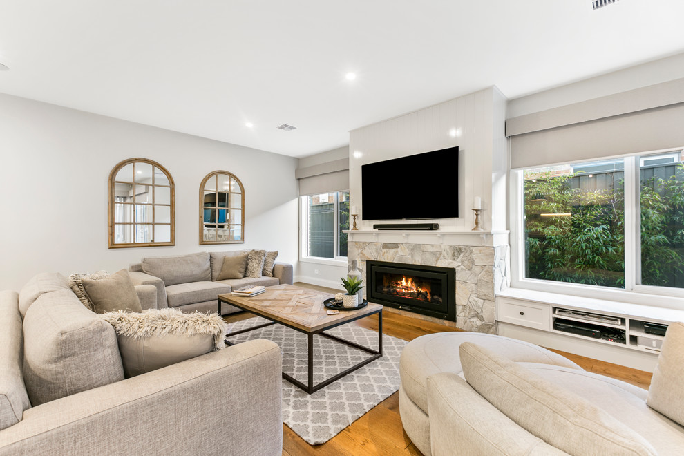 Design ideas for a large transitional open concept family room in Melbourne with white walls, a standard fireplace, a stone fireplace surround, a wall-mounted tv, medium hardwood floors and yellow floor.