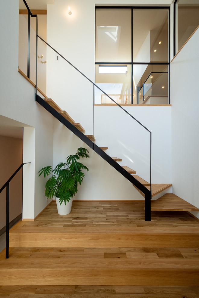 Inspiration för minimalistiska flytande trappor i trä, med öppna sättsteg och räcke i metall