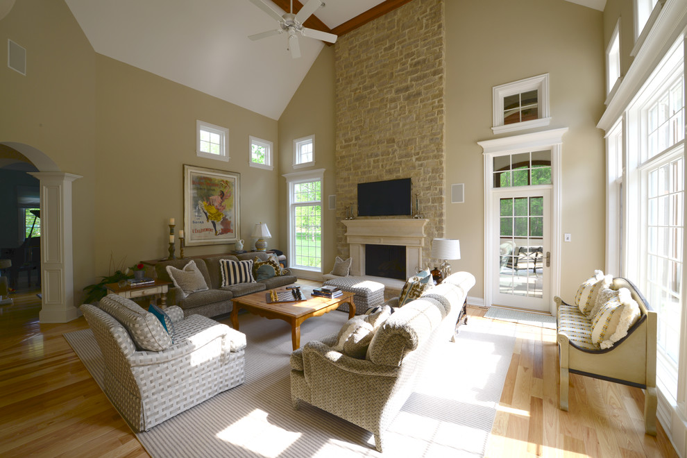 Family room - huge traditional open concept light wood floor family room idea in Indianapolis with beige walls, a standard fireplace, a stone fireplace and a wall-mounted tv