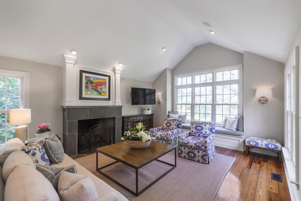 Large traditional open concept living room in DC Metro with a library, white walls, dark hardwood floors, a standard fireplace, a stone fireplace surround, a wall-mounted tv and red floor.
