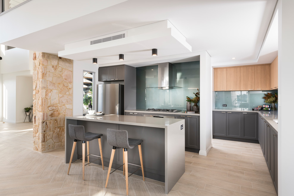 Inspiration for a contemporary l-shaped open plan kitchen in Perth with grey cabinets, blue splashback, stainless steel appliances, light hardwood floors, with island, beige floor, shaker cabinets and glass sheet splashback.