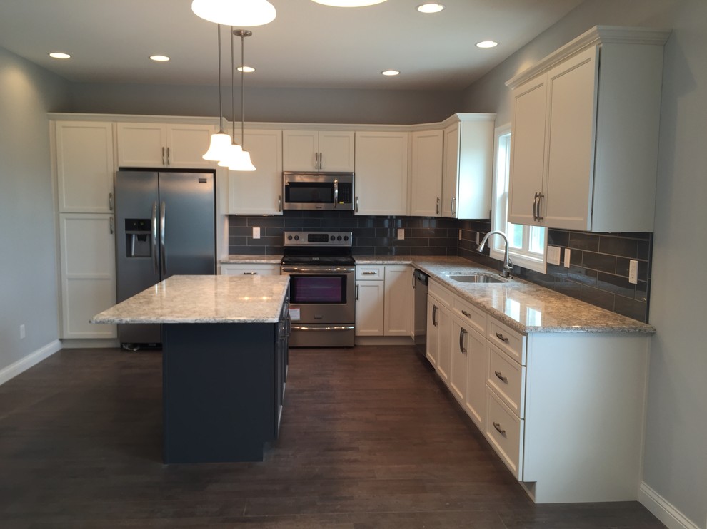 Inspiration for a large transitional l-shaped open concept kitchen remodel with an undermount sink, raised-panel cabinets, white cabinets, quartz countertops, gray backsplash, stainless steel appliances and an island