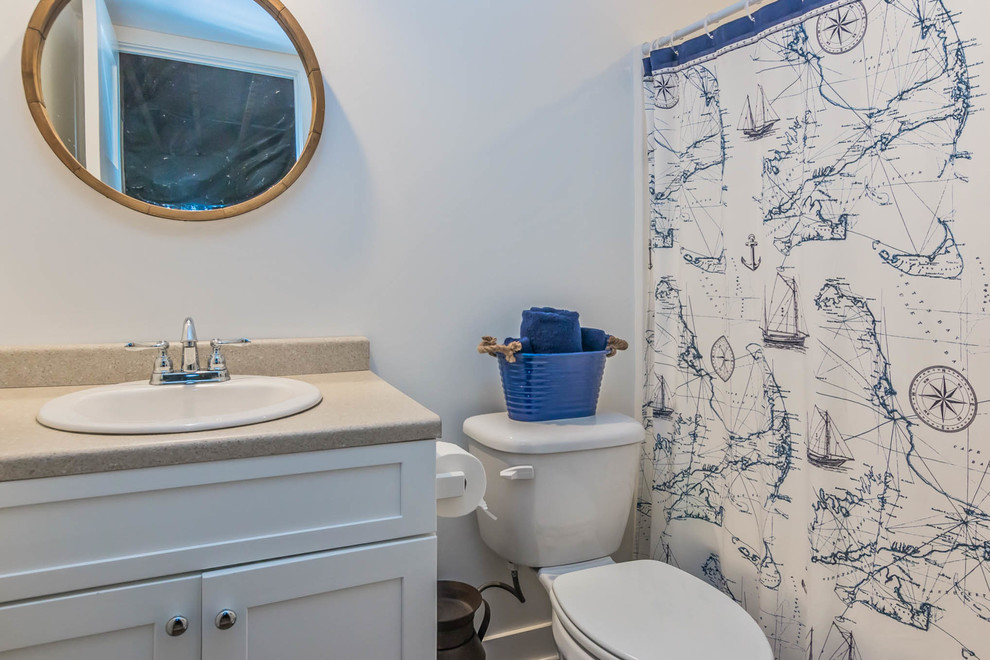 Photo of a mid-sized country 3/4 bathroom in Grand Rapids with shaker cabinets, white cabinets, an alcove tub, a shower/bathtub combo, a two-piece toilet, white walls, porcelain floors, a drop-in sink and engineered quartz benchtops.