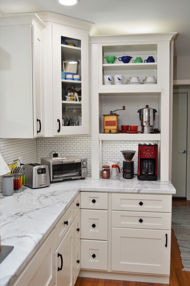 Inspiration for a large transitional u-shaped eat-in kitchen in Indianapolis with an undermount sink, recessed-panel cabinets, white cabinets, solid surface benchtops, white splashback, subway tile splashback, stainless steel appliances, medium hardwood floors, with island, brown floor and grey benchtop.