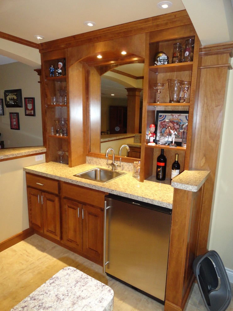 Photo of a transitional u-shaped wet bar in St Louis with a drop-in sink, raised-panel cabinets, laminate benchtops and porcelain floors.
