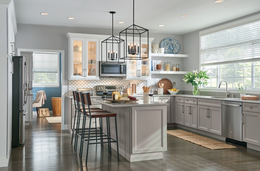 Example of a large trendy l-shaped eat-in kitchen design with an undermount sink, recessed-panel cabinets, white cabinets, white backsplash, stainless steel appliances and an island