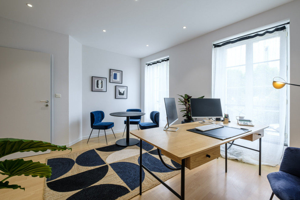 Ejemplo de despacho actual de tamaño medio sin chimenea con paredes blancas, suelo laminado, escritorio independiente, suelo beige y papel pintado