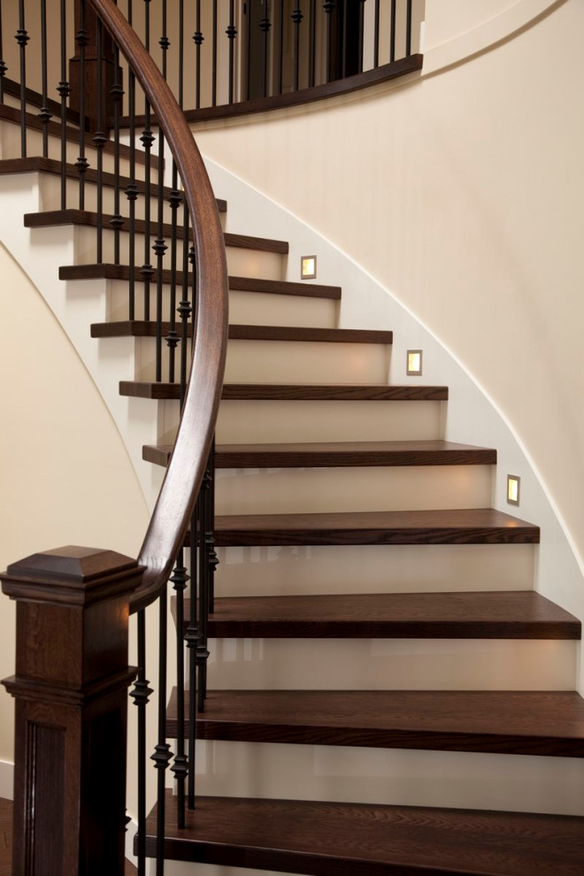 Imagen de escalera curva minimalista con escalones de madera, contrahuellas de madera y barandilla de madera