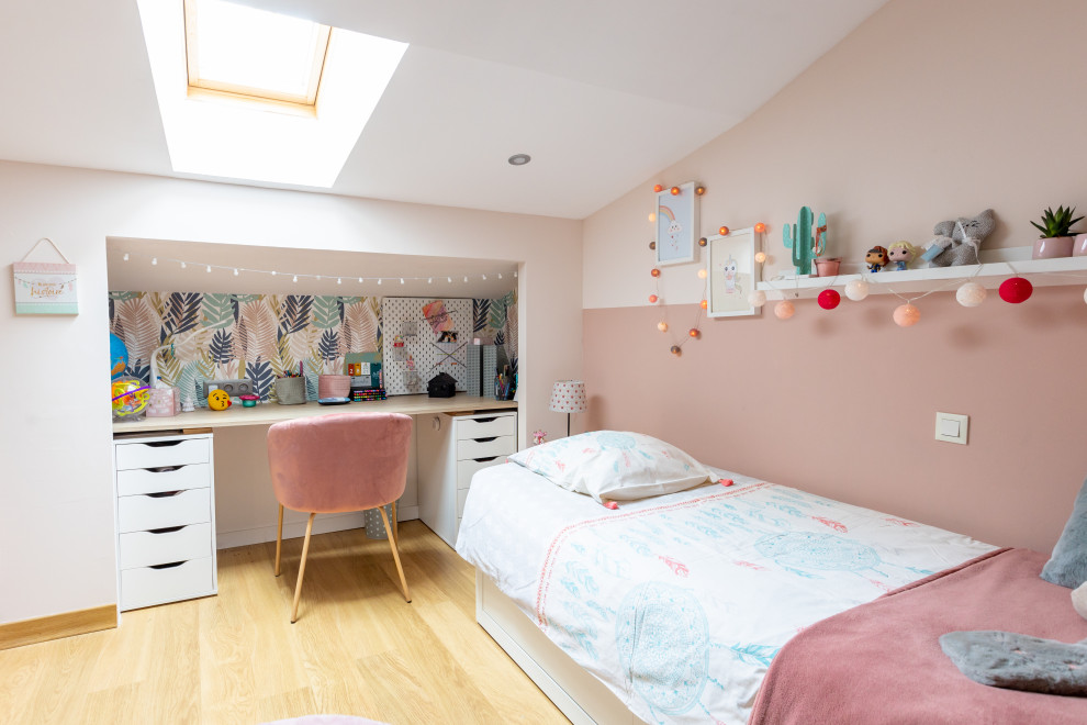 Foto på ett mellanstort funkis barnrum kombinerat med sovrum, med rosa väggar, ljust trägolv och beiget golv