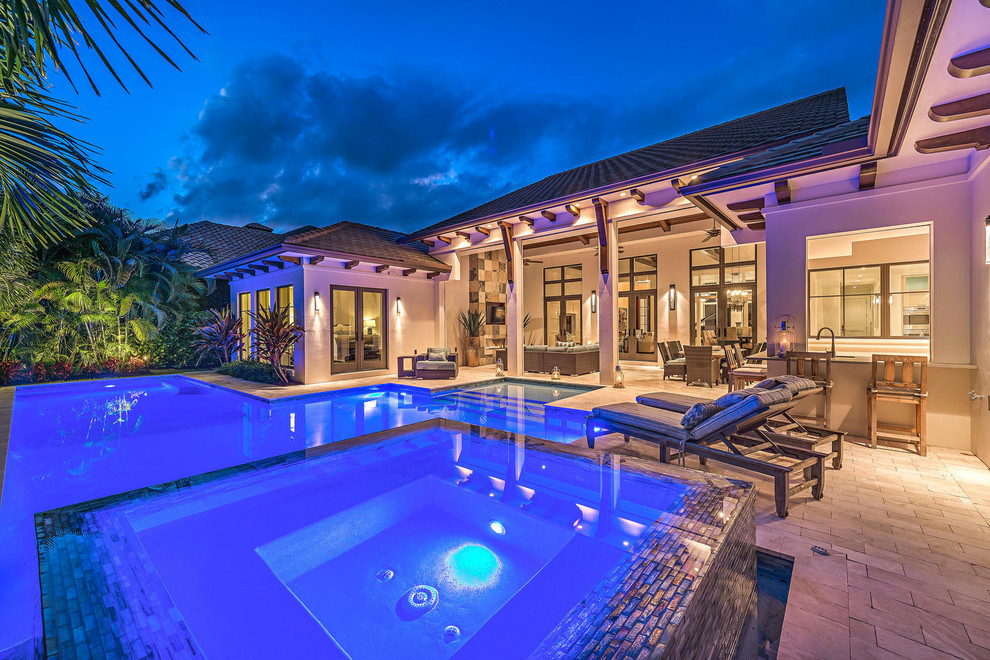 Inspiration for an expansive transitional backyard custom-shaped lap pool in Miami with a hot tub and natural stone pavers.