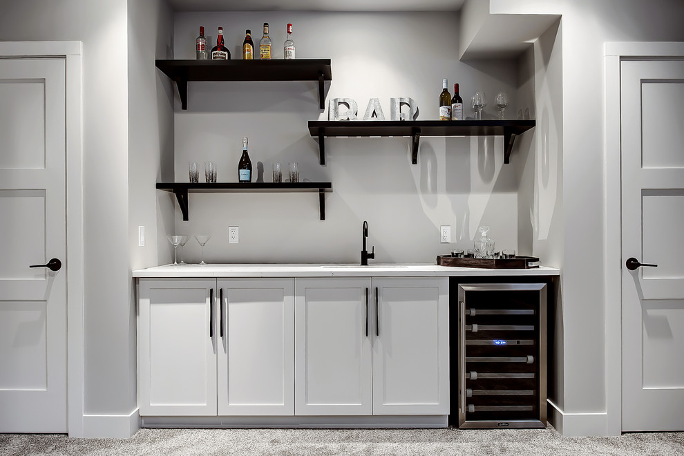This is an example of a transitional single-wall wet bar in Calgary with an undermount sink, shaker cabinets, white cabinets and carpet.
