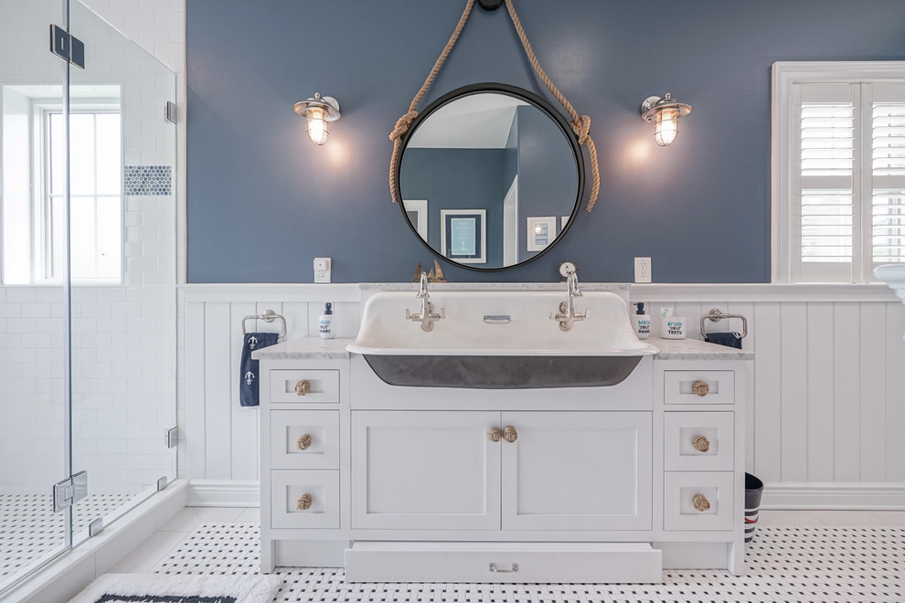 Photo of a beach style bathroom in Philadelphia with shaker cabinets, white cabinets, blue walls, mosaic tile floors, a trough sink, multi-coloured floor and grey benchtops.