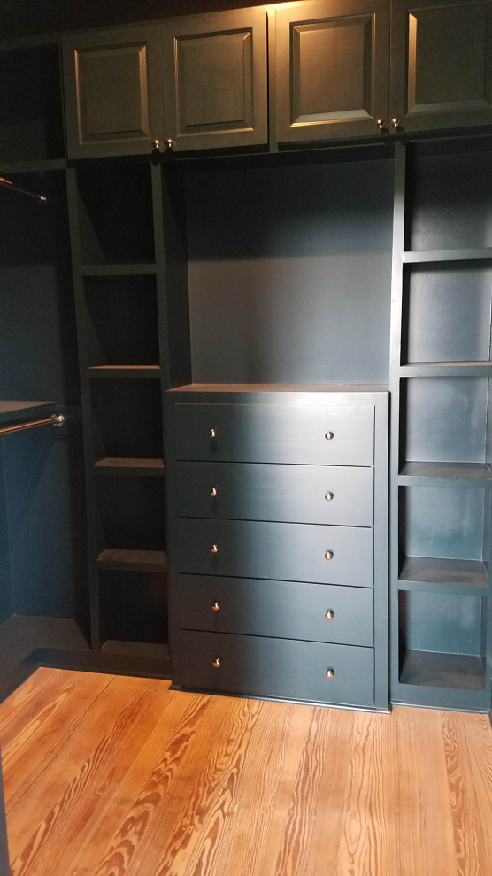 Inspiration for a mid-sized traditional walk-in wardrobe in Austin with raised-panel cabinets, black cabinets, medium hardwood floors and brown floor.