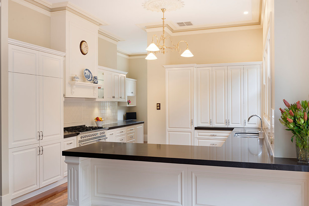Design ideas for a contemporary u-shaped kitchen pantry in Melbourne with an undermount sink, recessed-panel cabinets, white cabinets, quartz benchtops, beige splashback, ceramic splashback, white appliances, beige walls and medium hardwood floors.