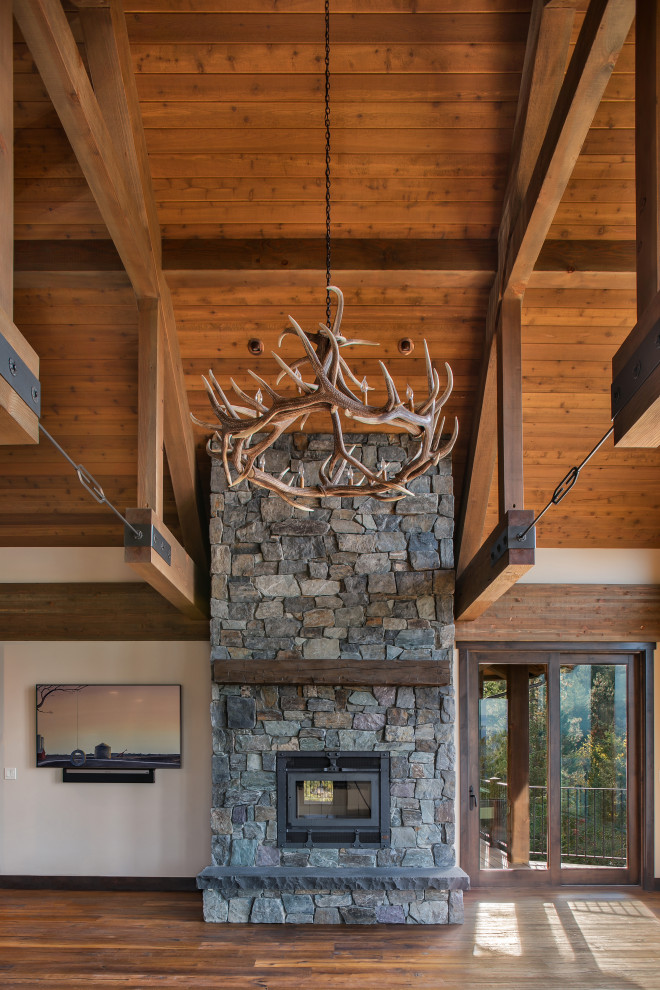 Inspiration for a mid-sized country open concept living room in Seattle with white walls, a wood stove, a stone fireplace surround and a wall-mounted tv.
