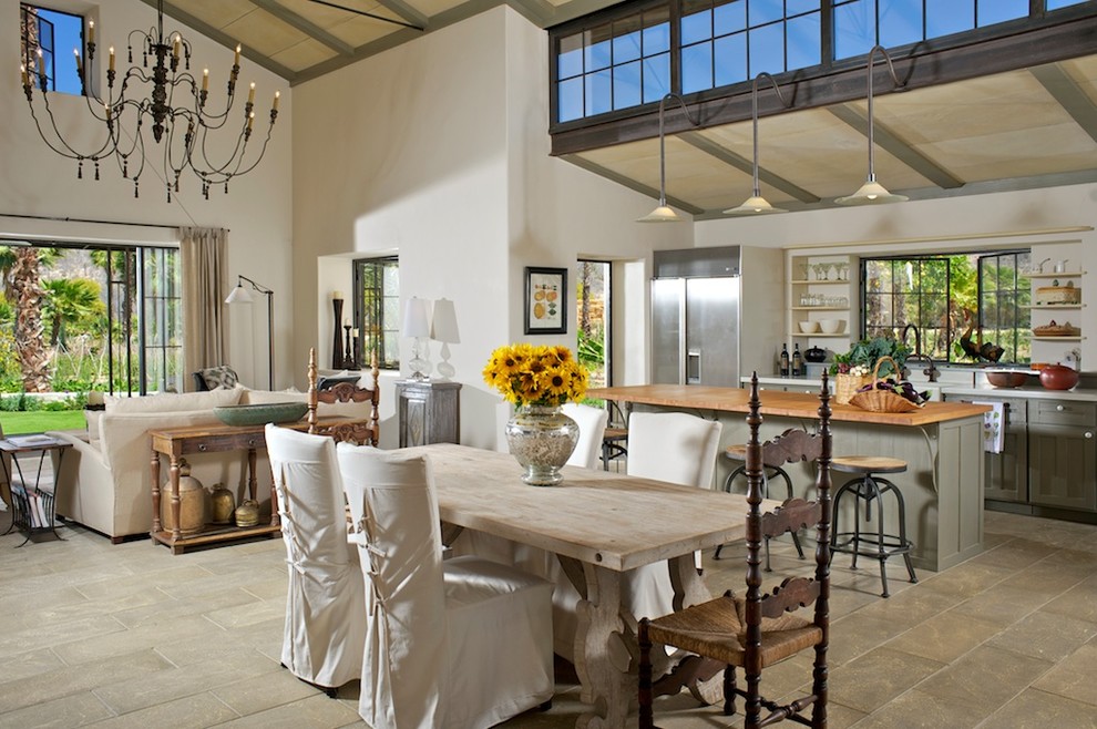 This is an example of a country open plan dining in Other with white walls, concrete floors and no fireplace.