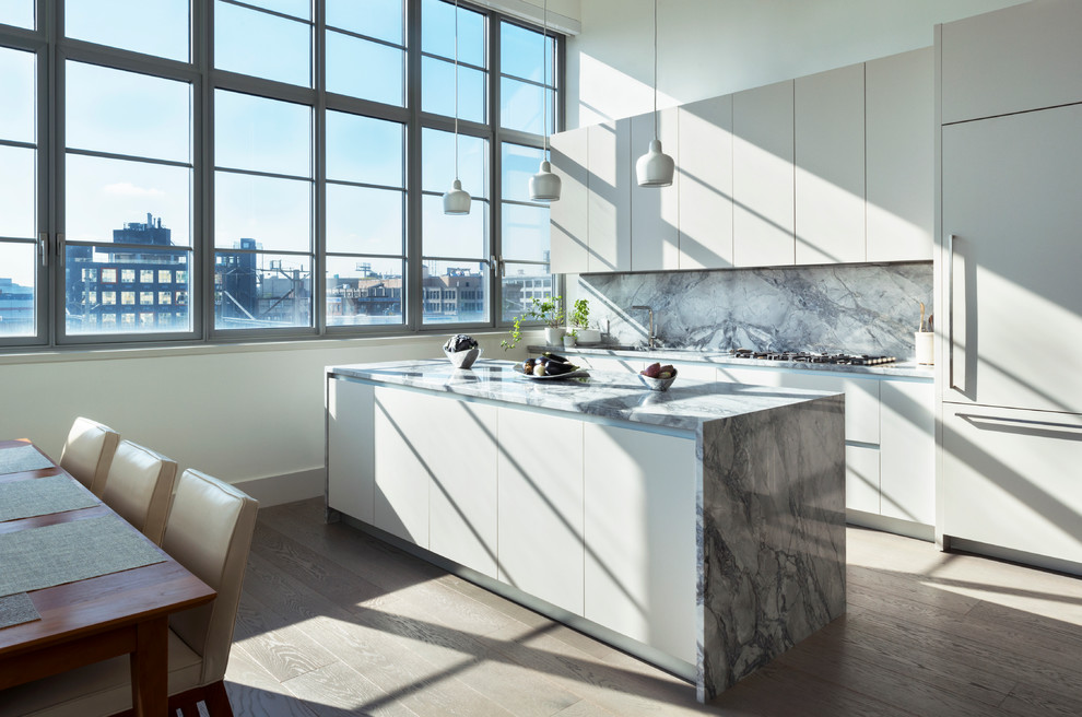 This is an example of a mid-sized contemporary galley open plan kitchen in New York with an undermount sink, flat-panel cabinets, quartzite benchtops, grey splashback, stone slab splashback, panelled appliances, with island, grey cabinets and dark hardwood floors.