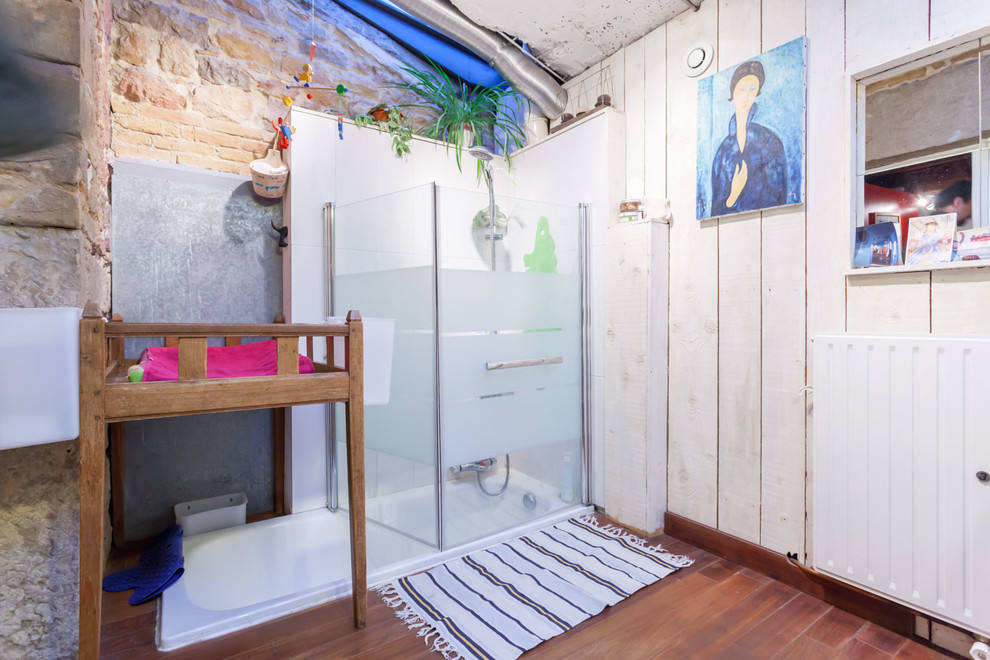 This is an example of a mid-sized eclectic 3/4 bathroom in Lyon with an undermount tub, a shower/bathtub combo, white walls and medium hardwood floors.