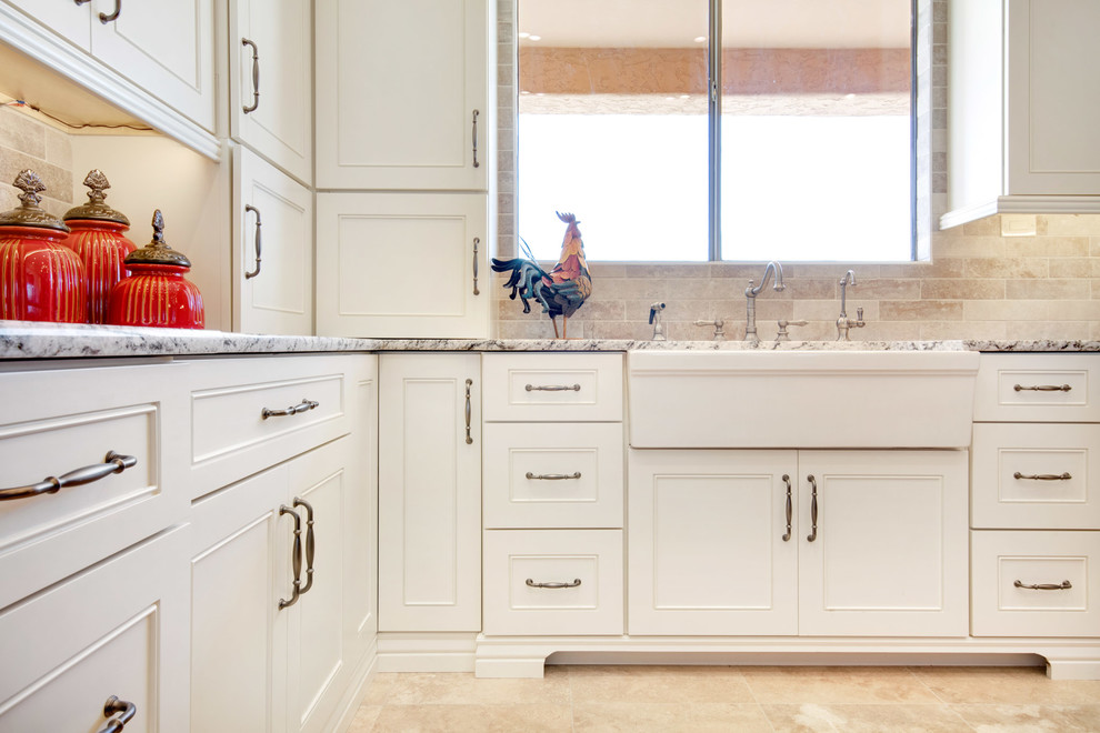Example of a large transitional u-shaped travertine floor and beige floor open concept kitchen design in Phoenix with a farmhouse sink, recessed-panel cabinets, white cabinets, granite countertops, gray backsplash, porcelain backsplash, stainless steel appliances, an island and multicolored countertops