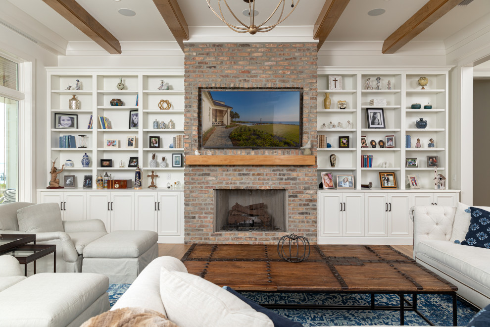 Inspiration for a large traditional open concept living room in New Orleans with white walls, medium hardwood floors, a standard fireplace, a brick fireplace surround, a wall-mounted tv, brown floor and exposed beam.