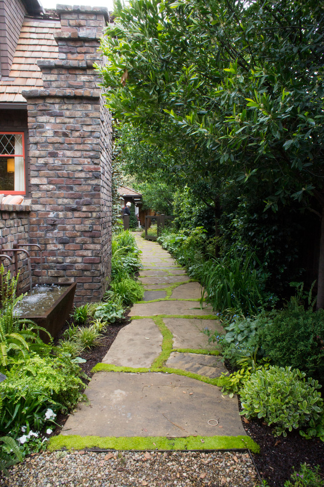 This is an example of an arts and crafts side yard garden in San Francisco with a garden path and natural stone pavers.