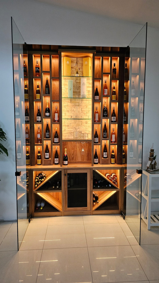This is an example of a small modern wine cellar in Brisbane with ceramic floors, display racks and beige floor.