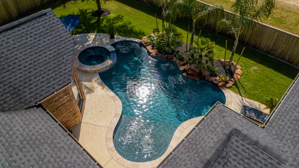 Mid-sized tropical backyard custom-shaped pool in Houston with decking.