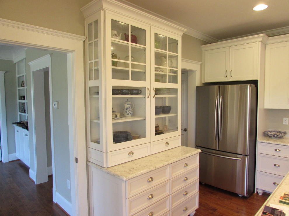 This is an example of a mid-sized traditional l-shaped kitchen pantry in DC Metro with white cabinets, granite benchtops, stainless steel appliances, light hardwood floors and with island.