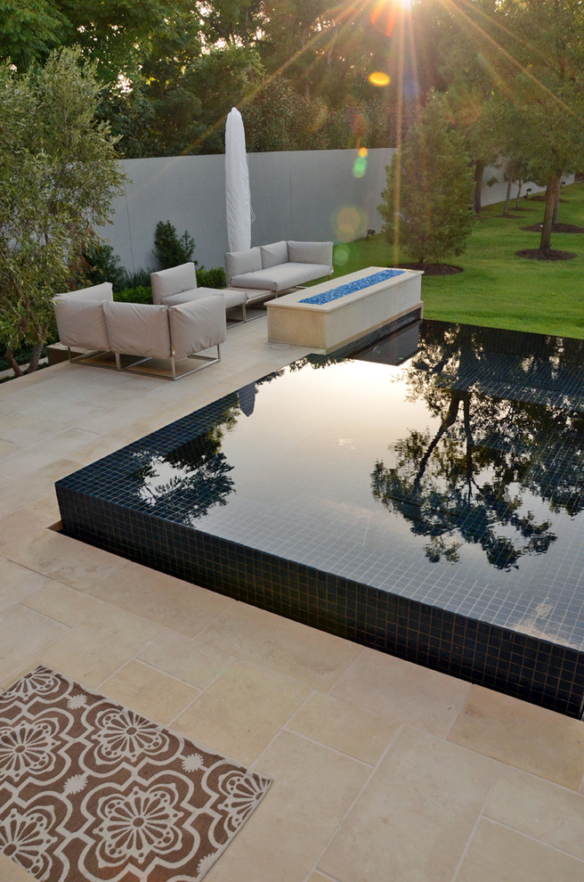 This is an example of a small modern backyard custom-shaped infinity pool in Houston with a water feature and tile.