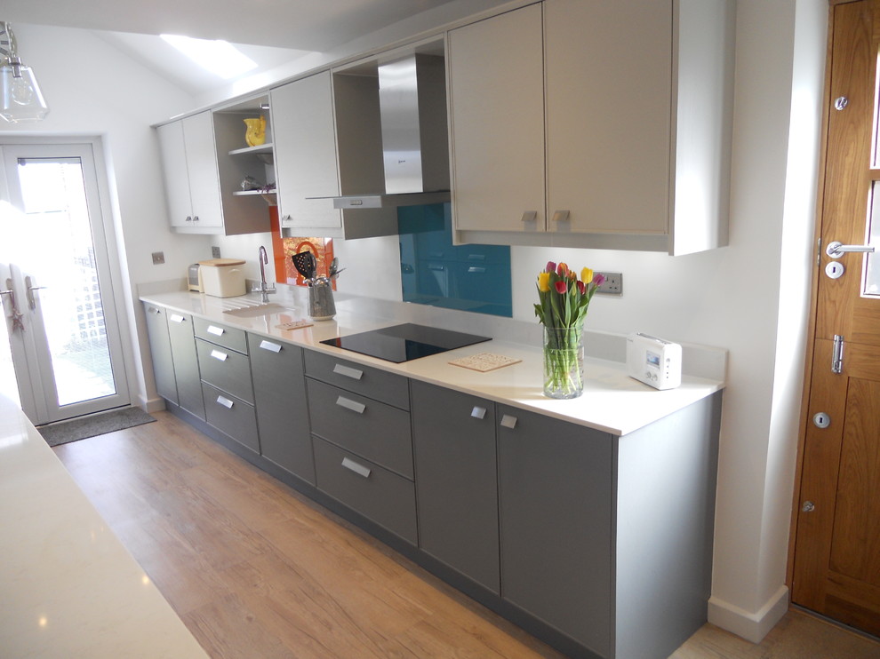 This is an example of a modern galley kitchen in West Midlands with shaker cabinets and glass sheet splashback.